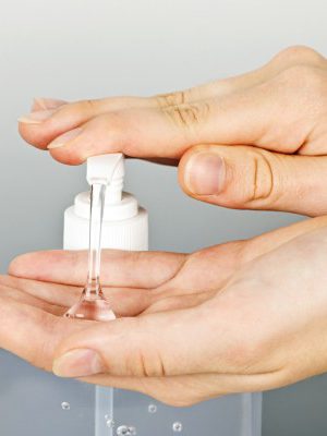 Female hands using hand sanitizer gel pump dispenser