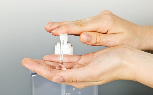 Female hands using hand sanitizer gel pump dispenser